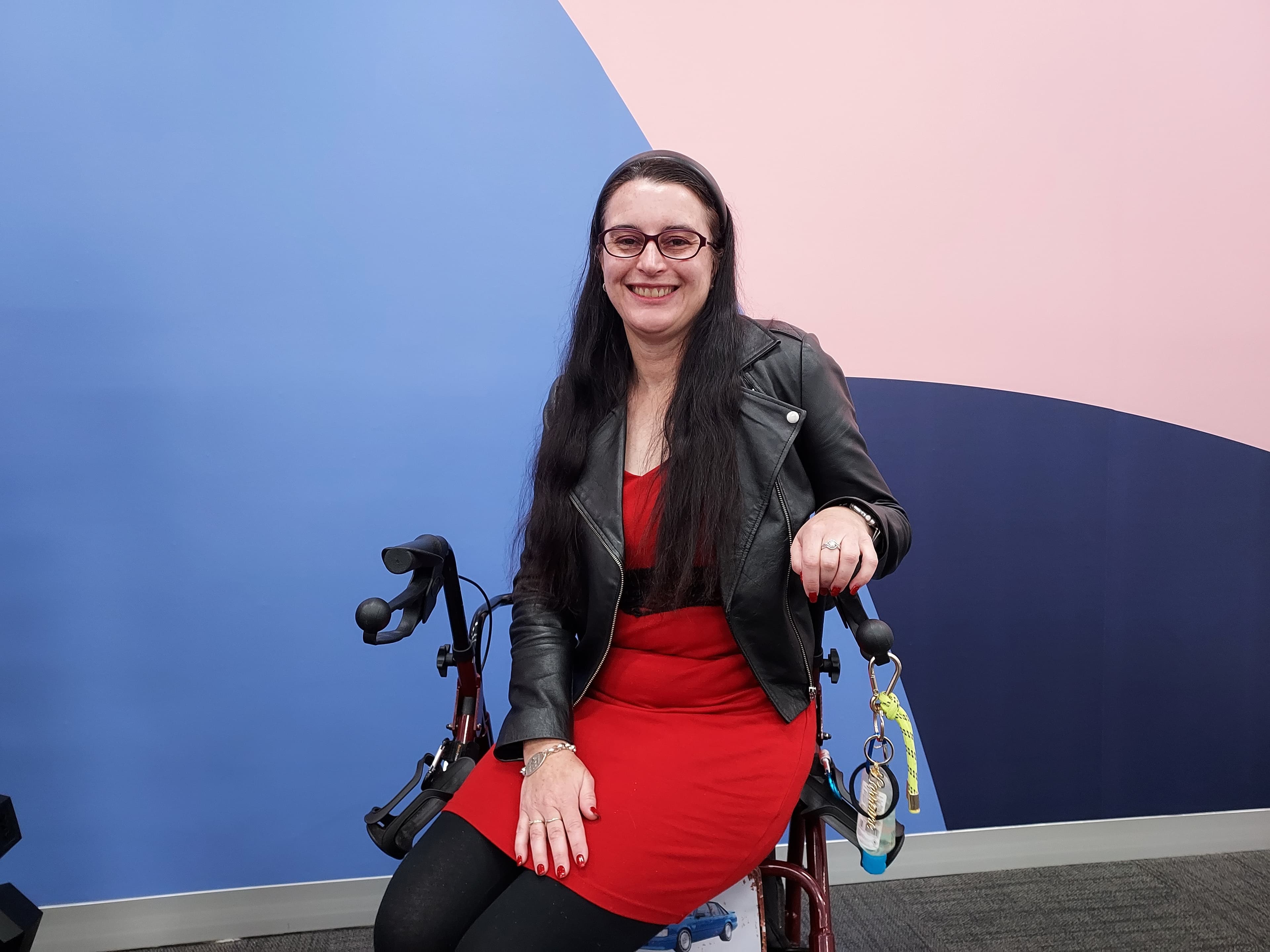 Lorraine who is a person living with MS is sitting on a wheelchair and smiling