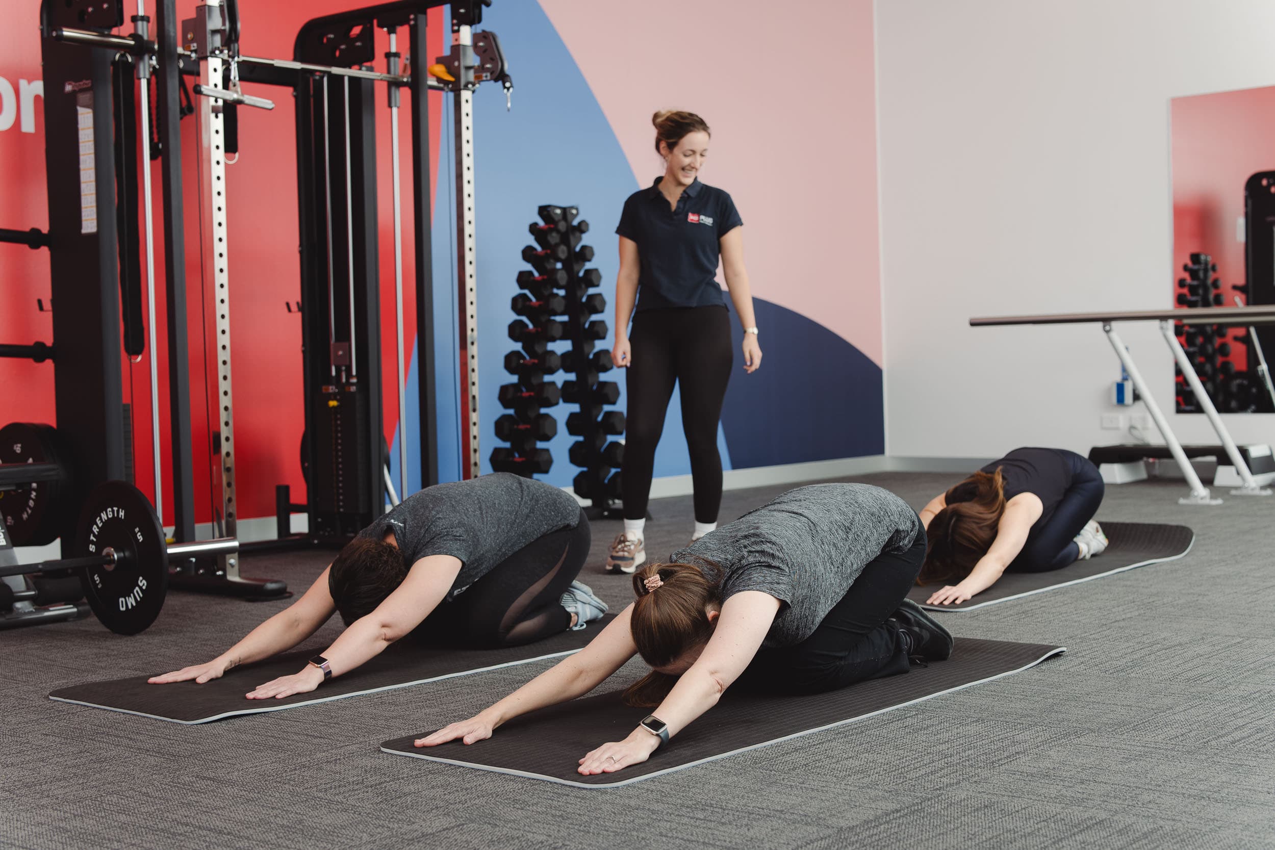 Three people doing yoga under instruction from an MS Plus Allied Health staff member.