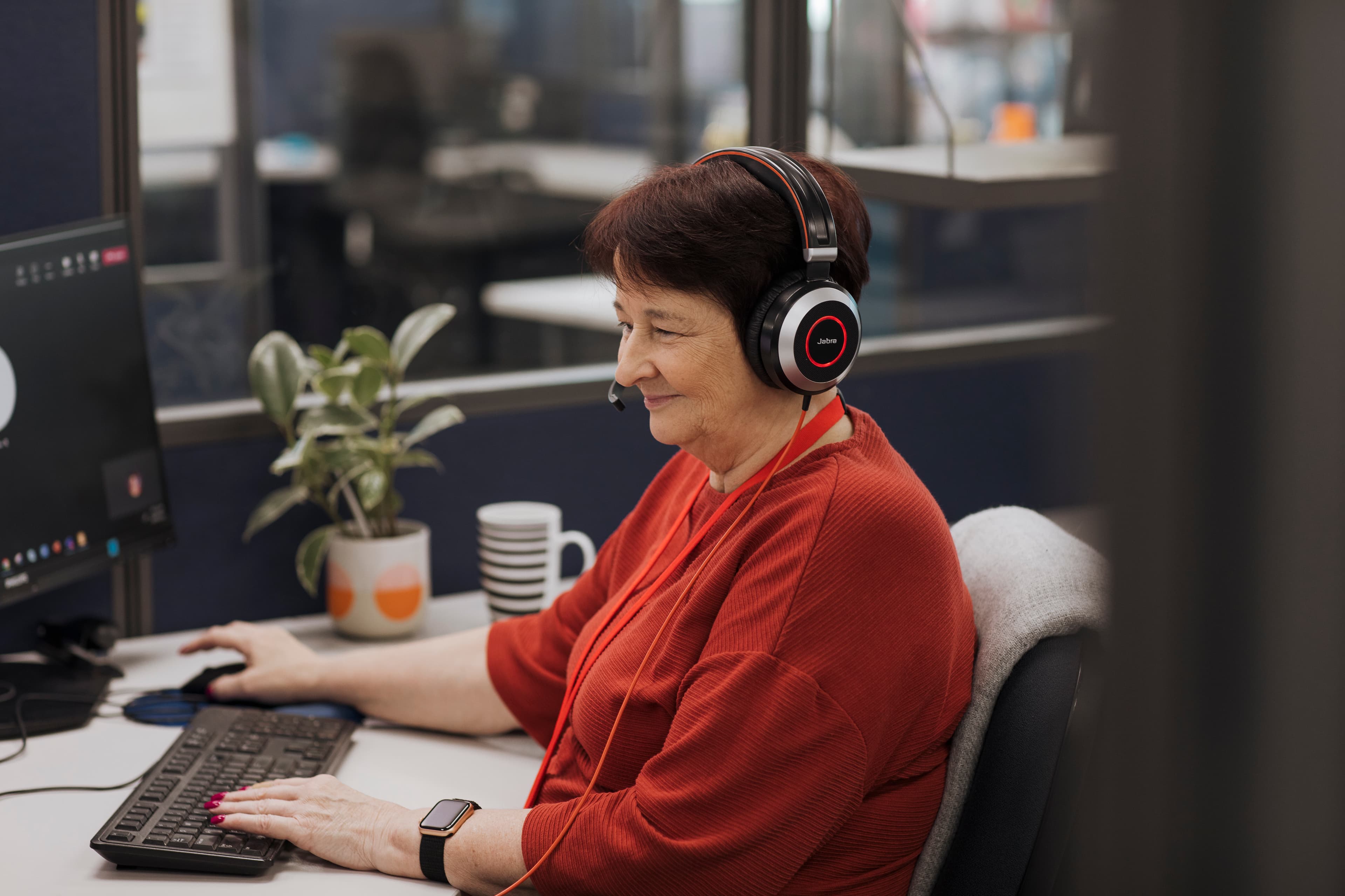 An MS Plus employee seated at her desk wearing a headset.