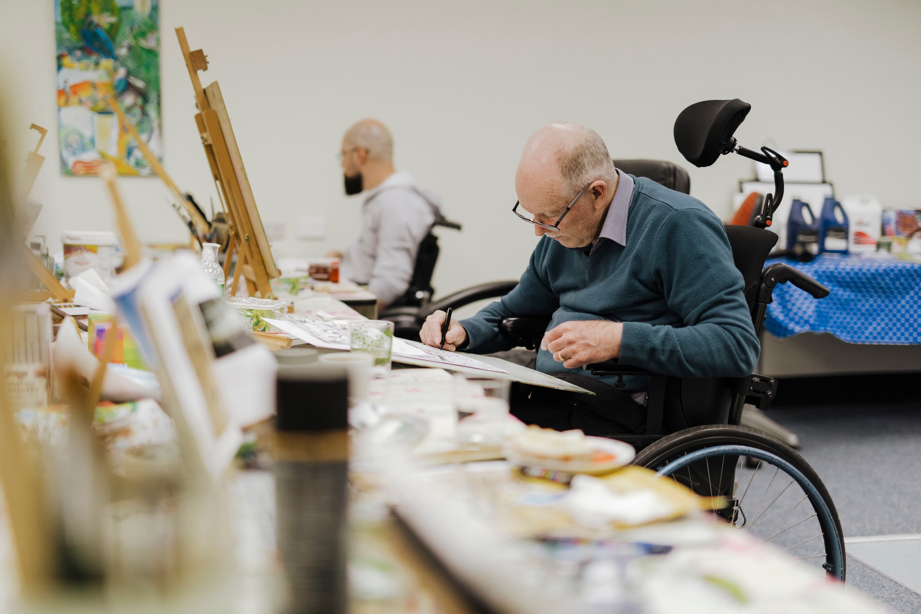 A man in wheelchair drawing on board