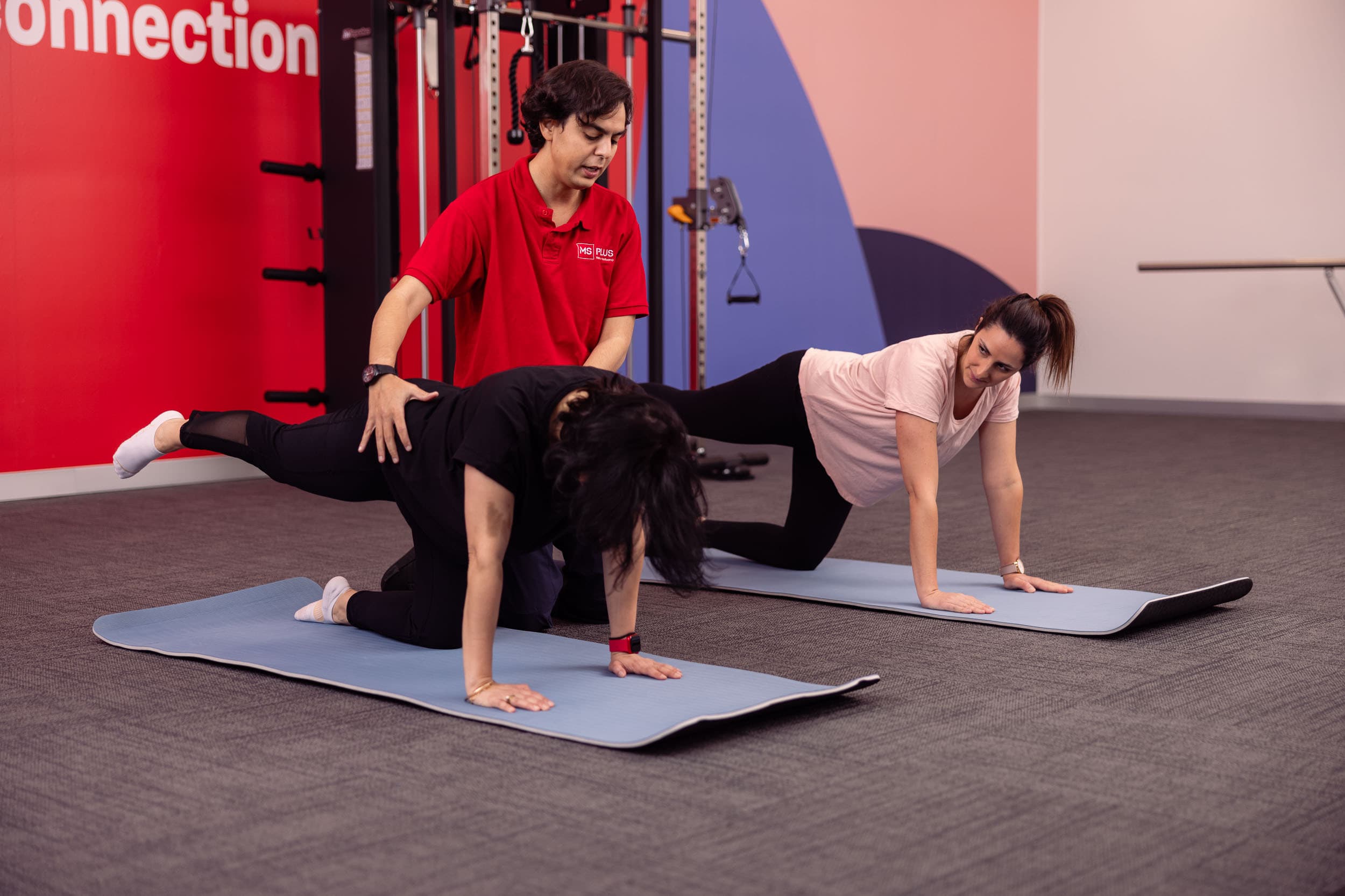 A neuro therapist providing Pilates instruction to two people.