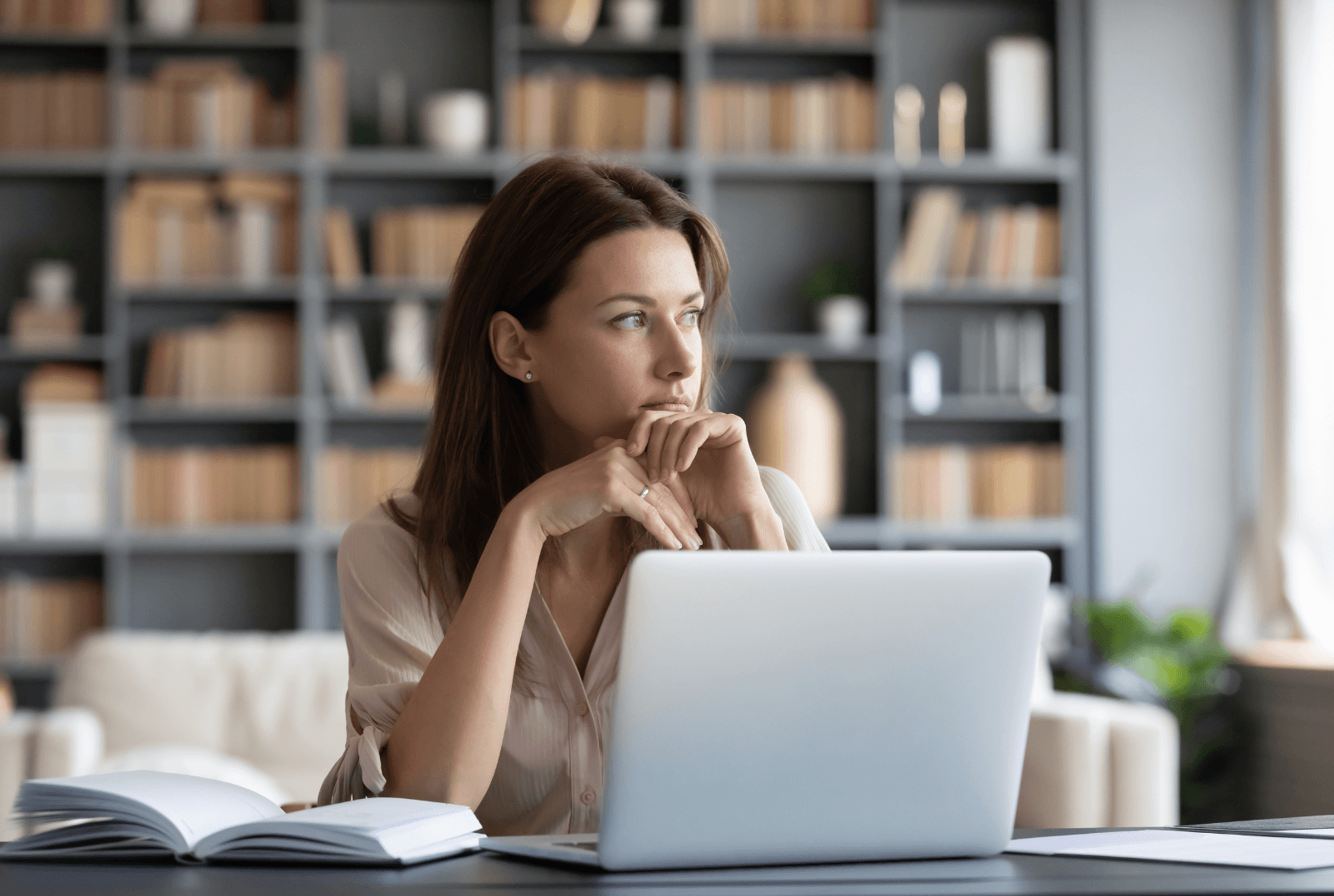 A woman seated at a desk with a laptop in front of her.