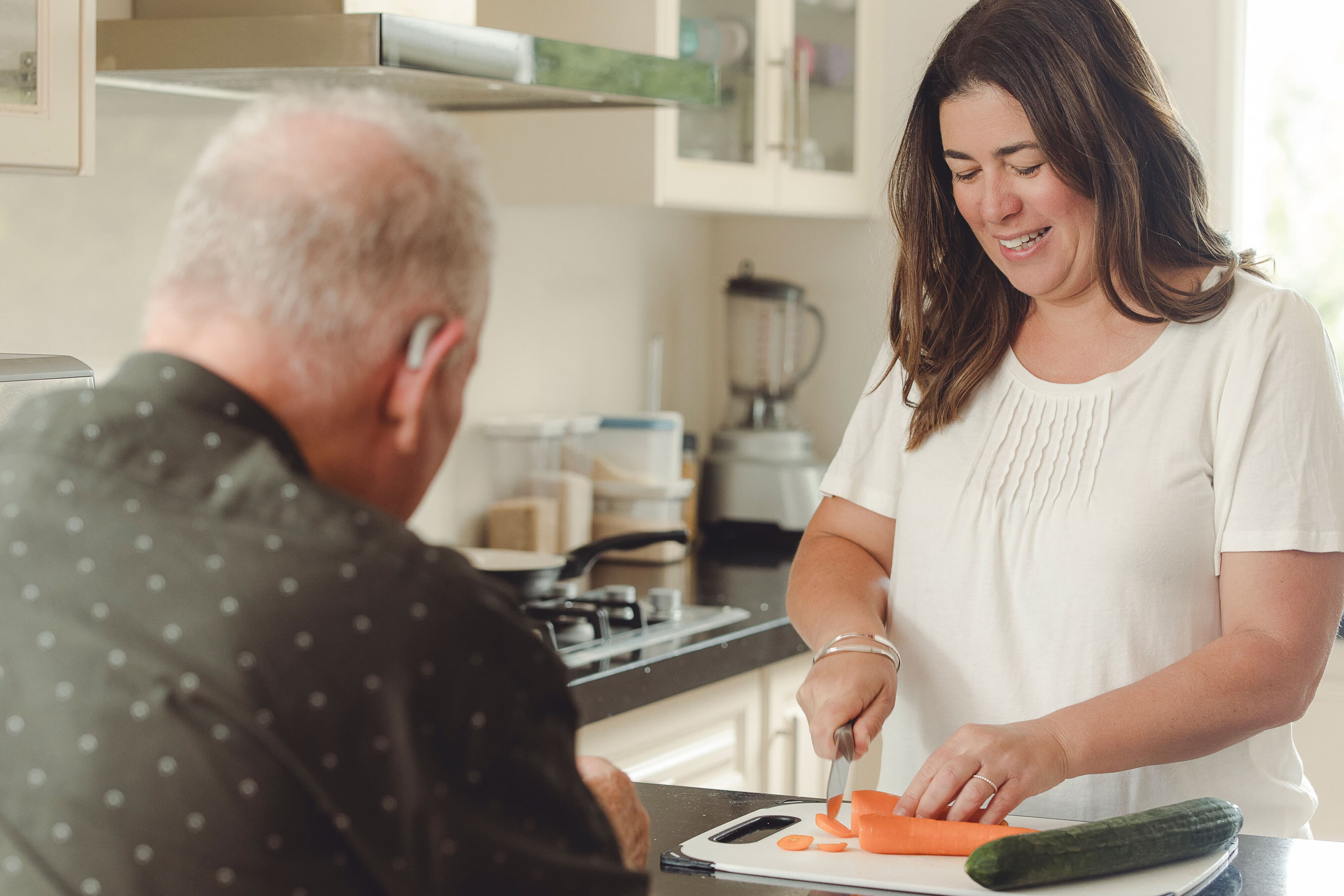 A support worker helping an elderly man with preparing food in his home.