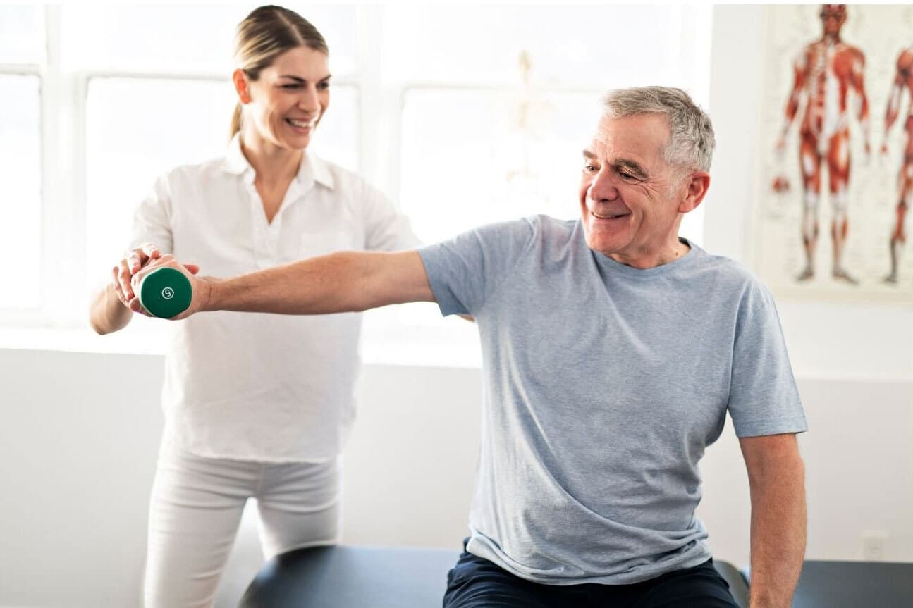 A physiotherapist is helping a man with exercises and lifting weight in his right hand