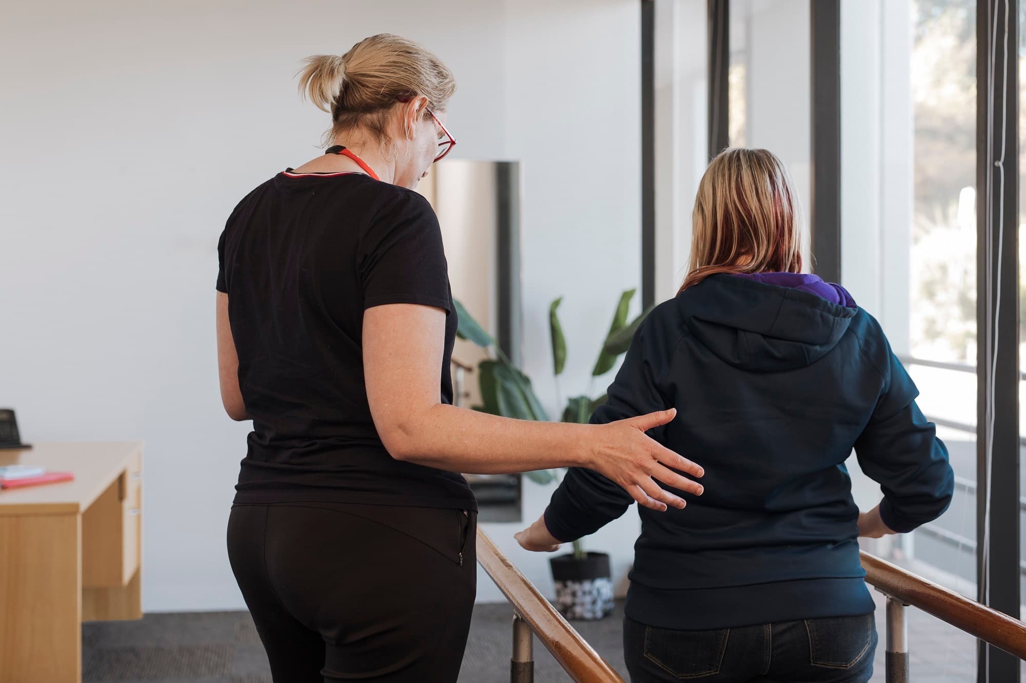 A MS PLus physiotherapist helping a woman walk
