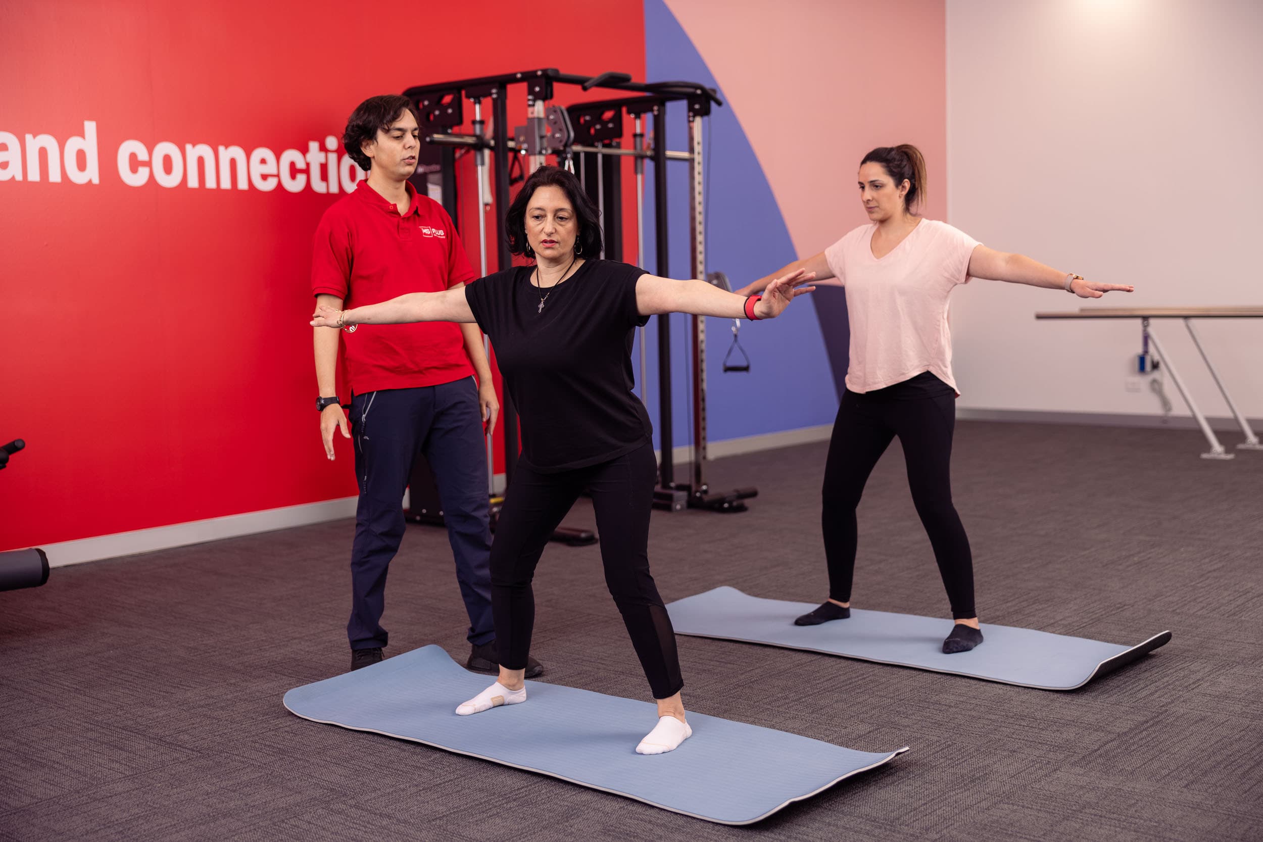 A neuro therapist providing Pilates instruction to two women.