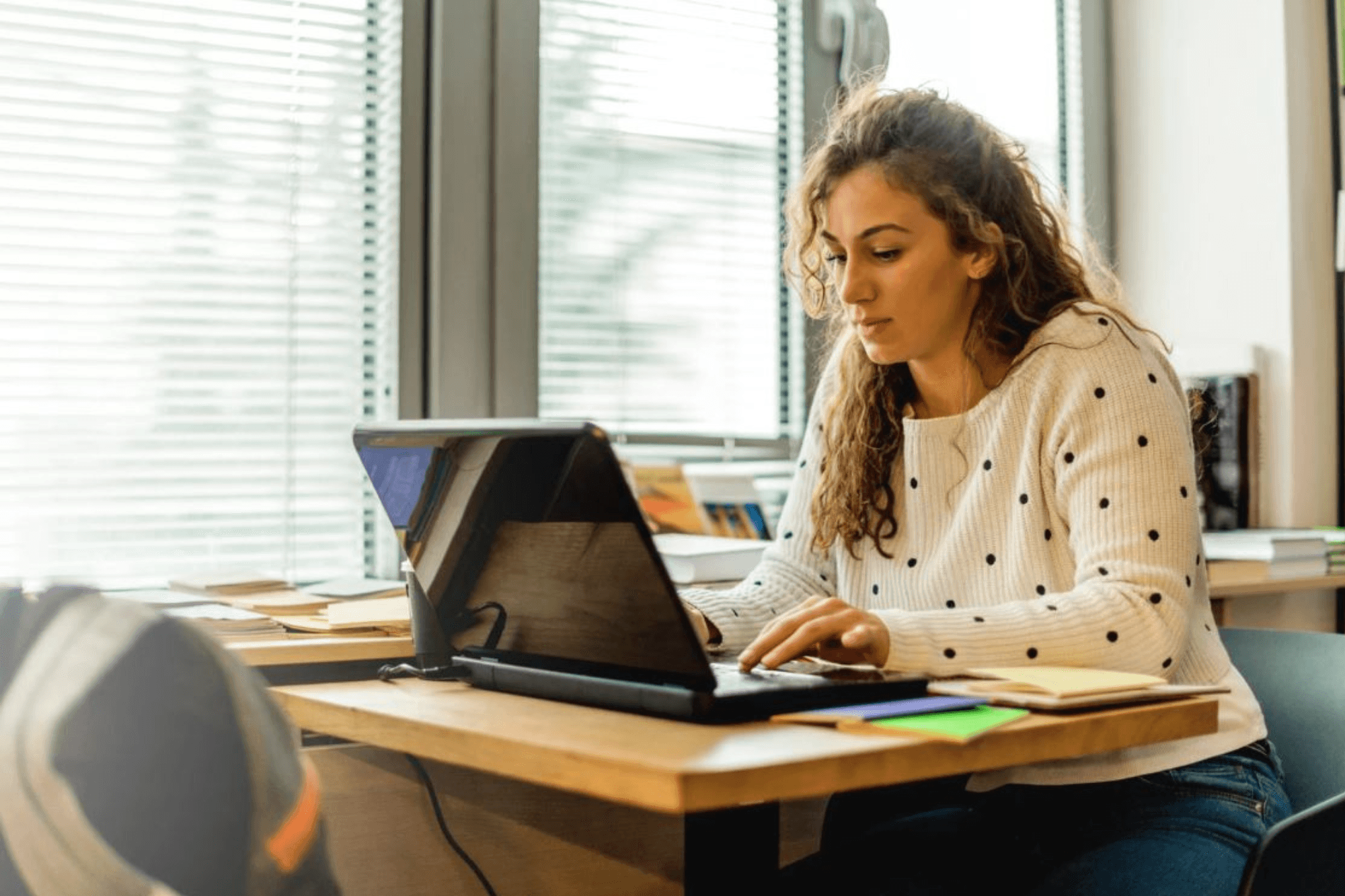 A woman seated at a small table using a laptop computer.