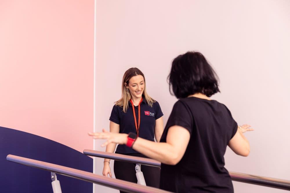 Exercise physio assisting client in gym