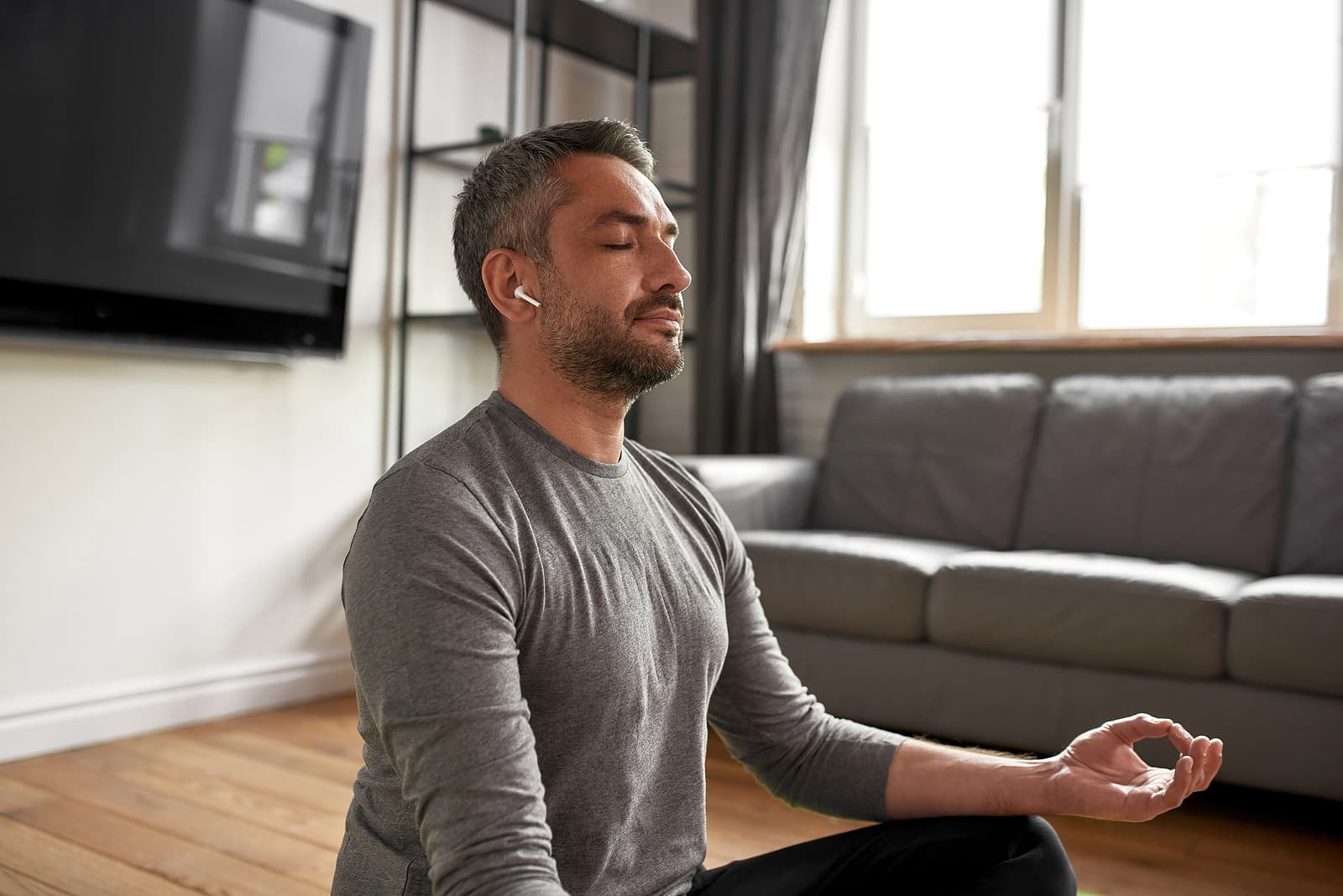 person sitting in lotus position meditation while listening to a earphones