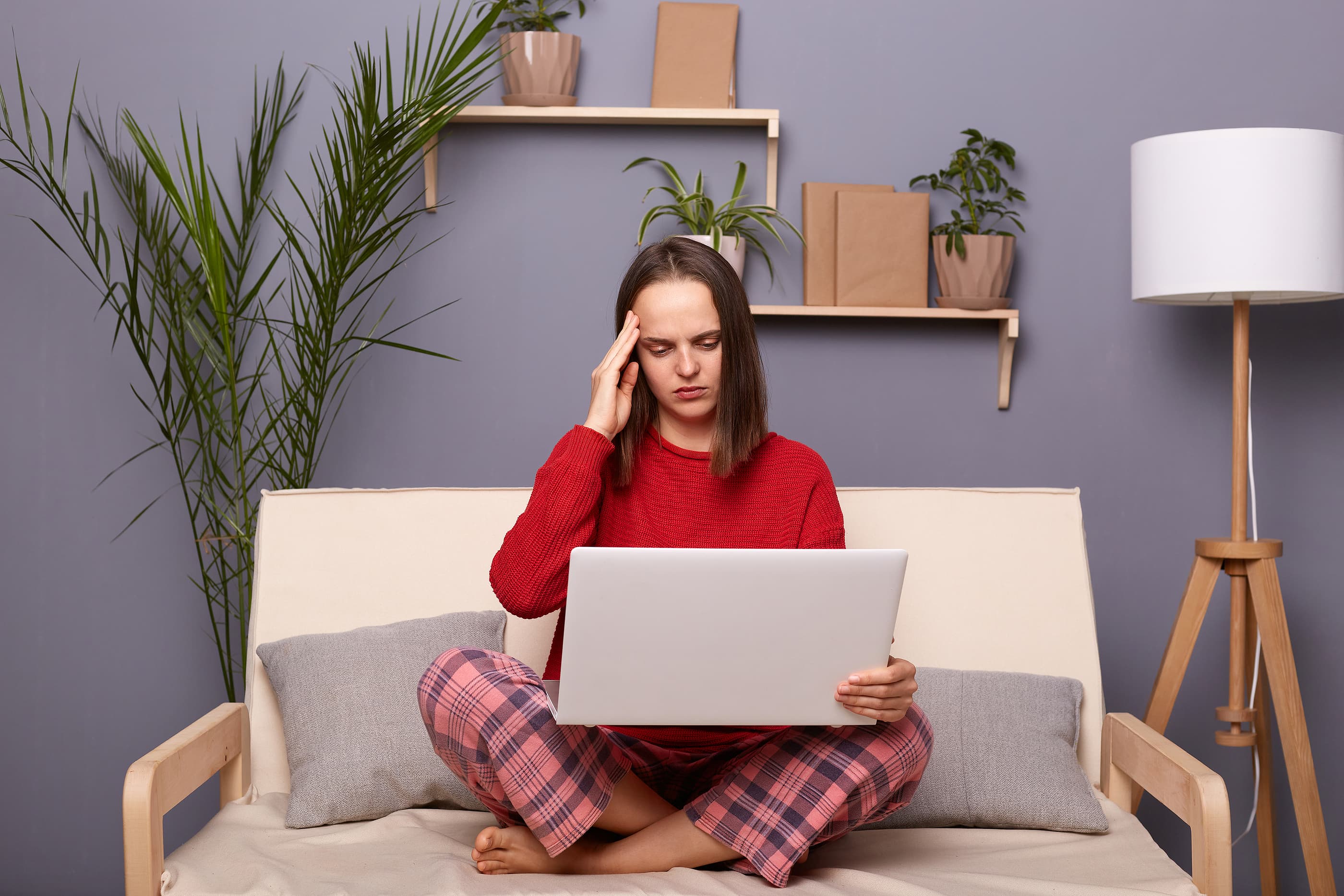Person in pajamas with laptop holding head