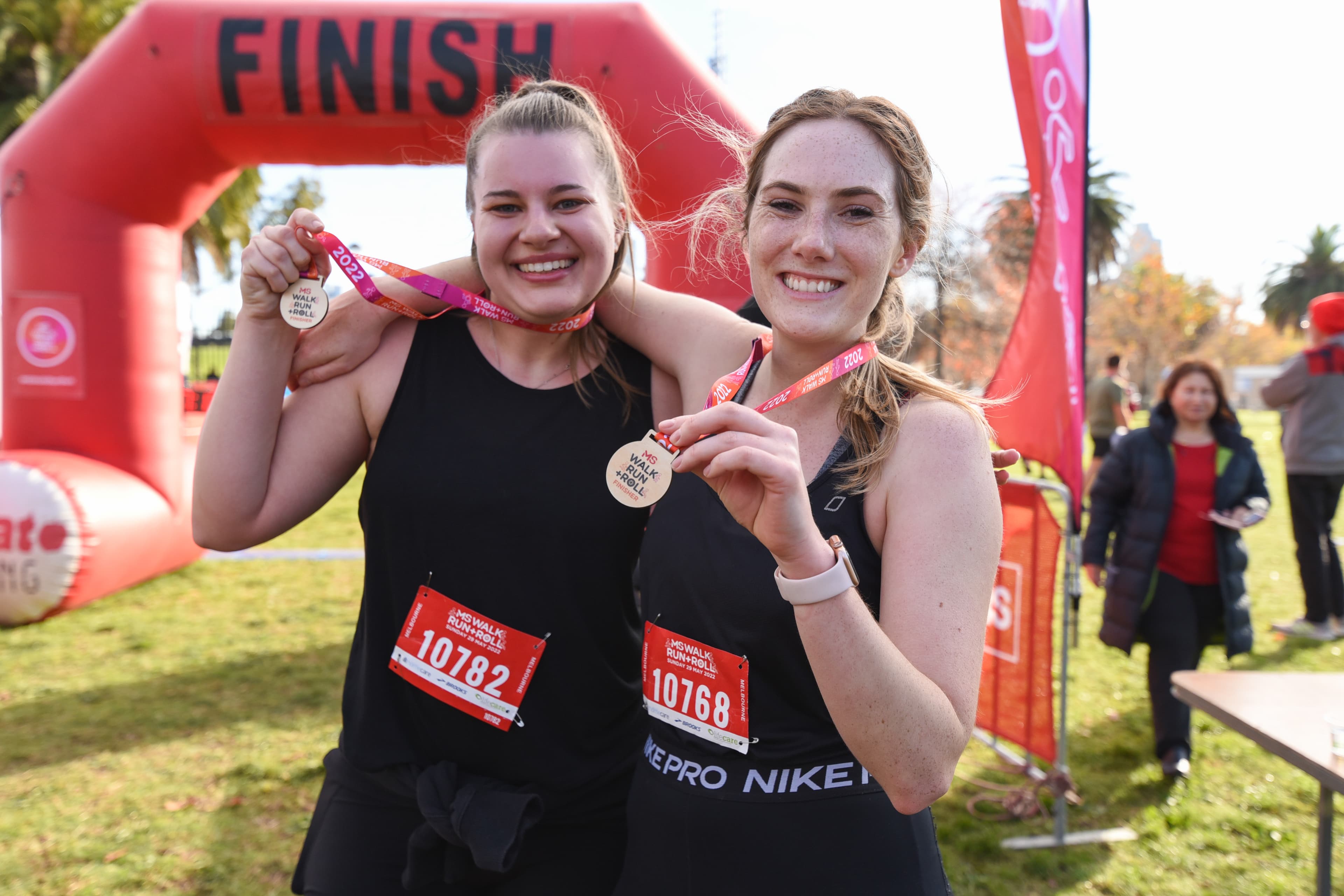 Two runners with MS Walk Run + Roll medals