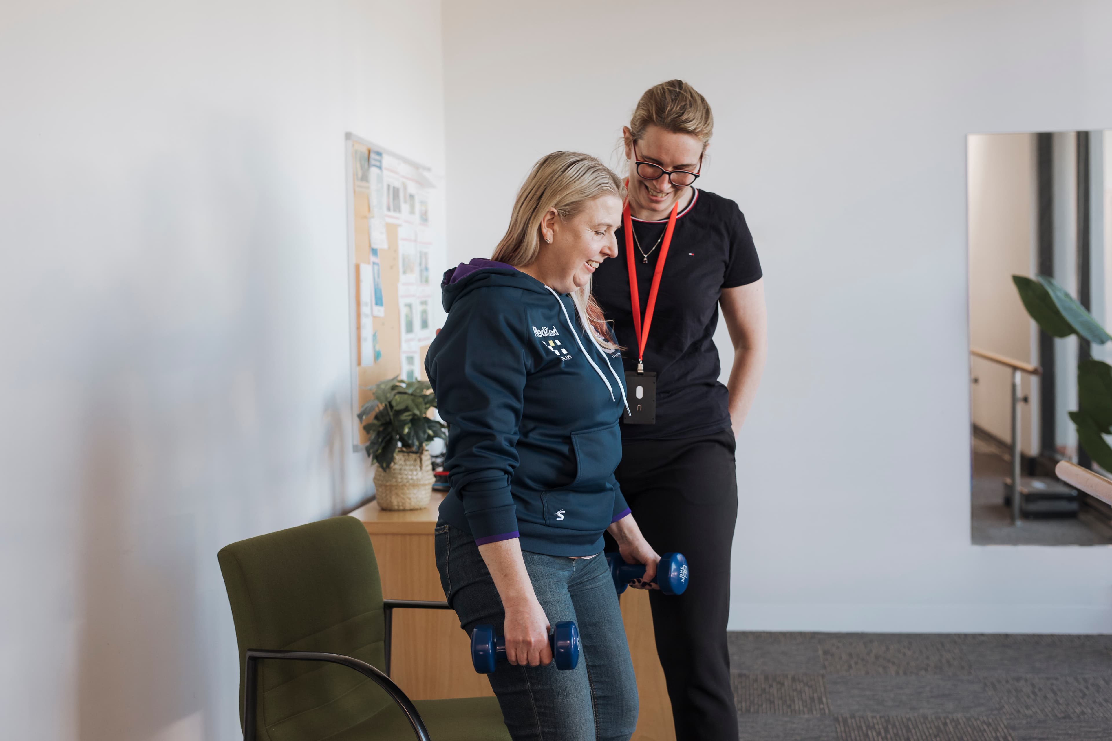 Exercise physiologist stands next to client holding weights
