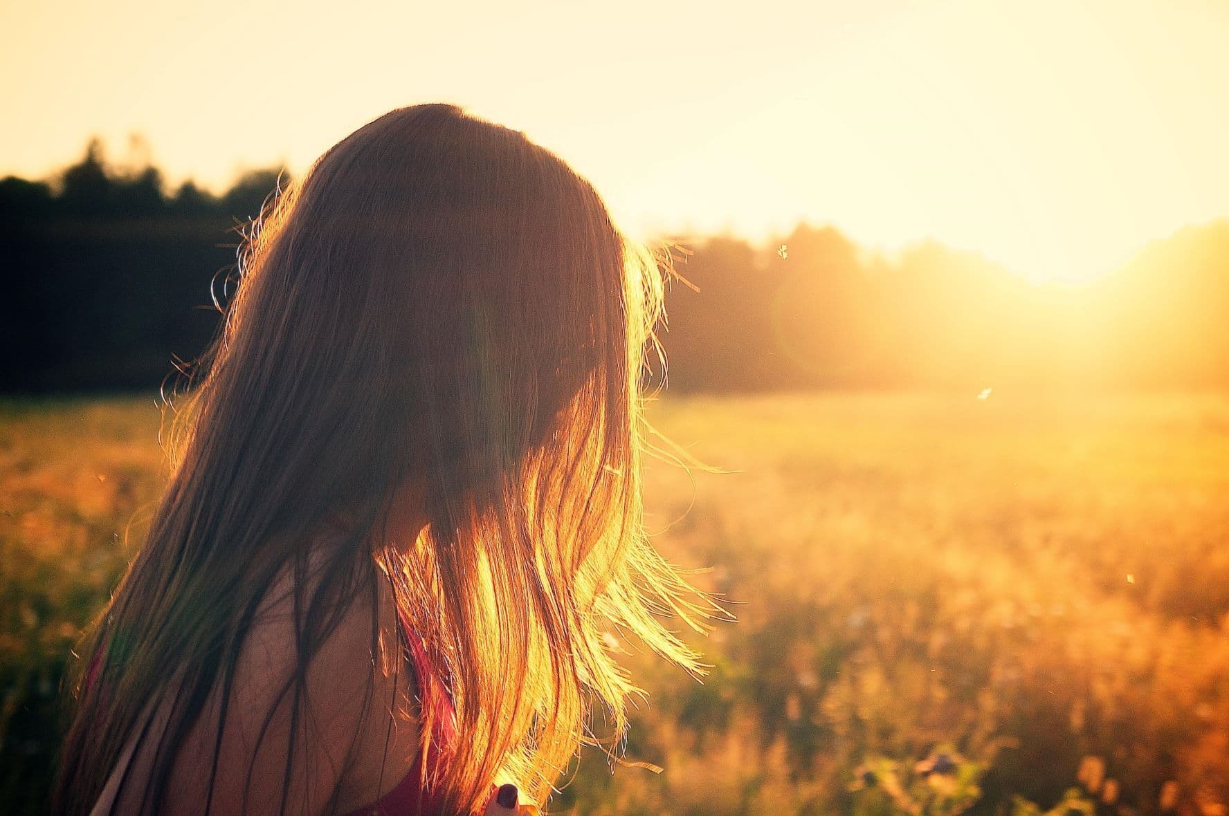 person with long hair standing in a field