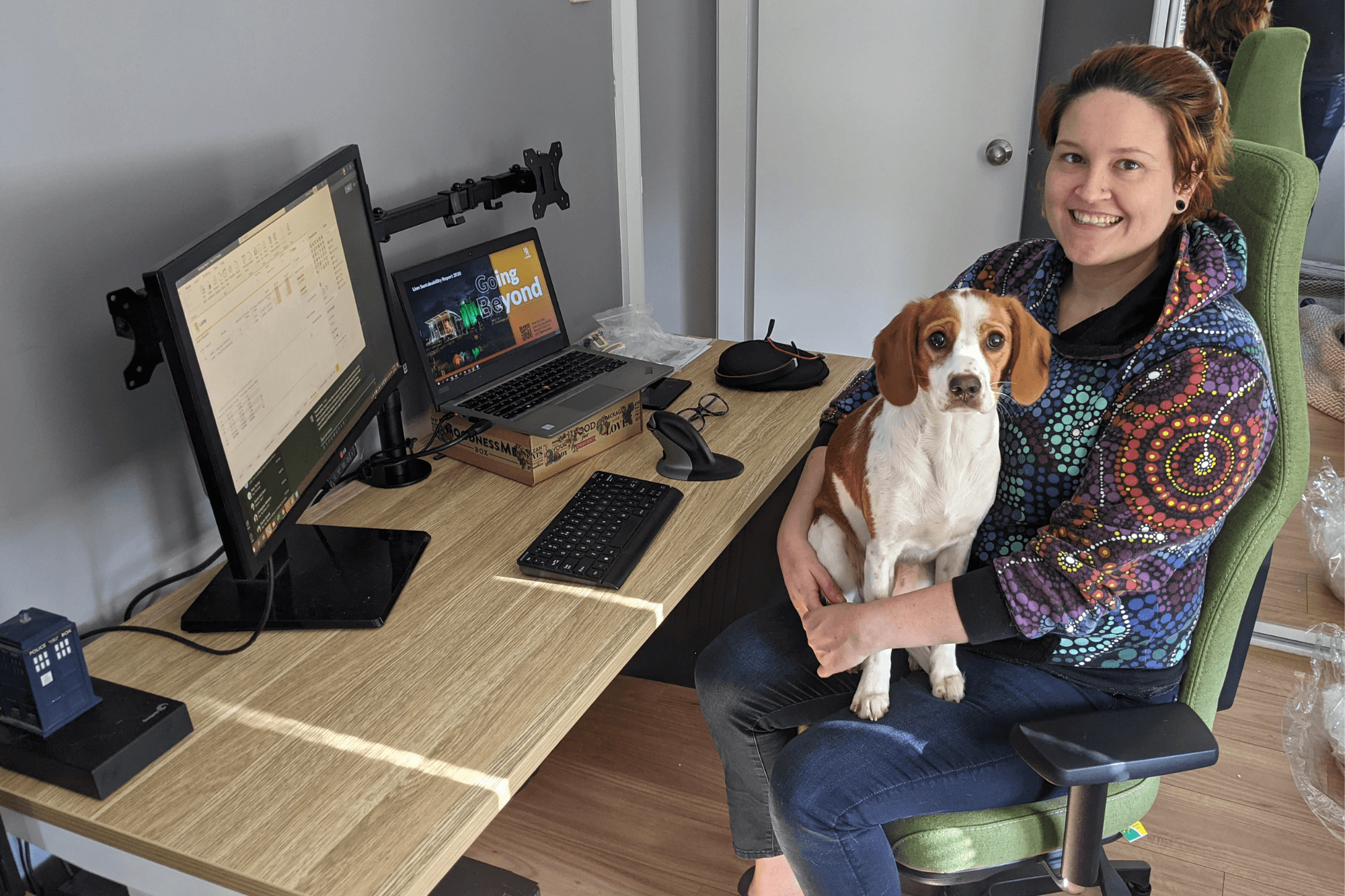 Tamara seated at her desk with her dog in her lap.