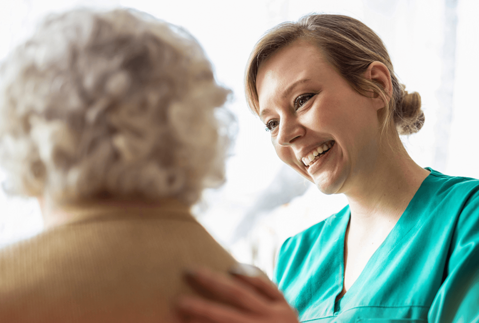A woman with her hand reassuringly on the shoulder of an elderly woman.
