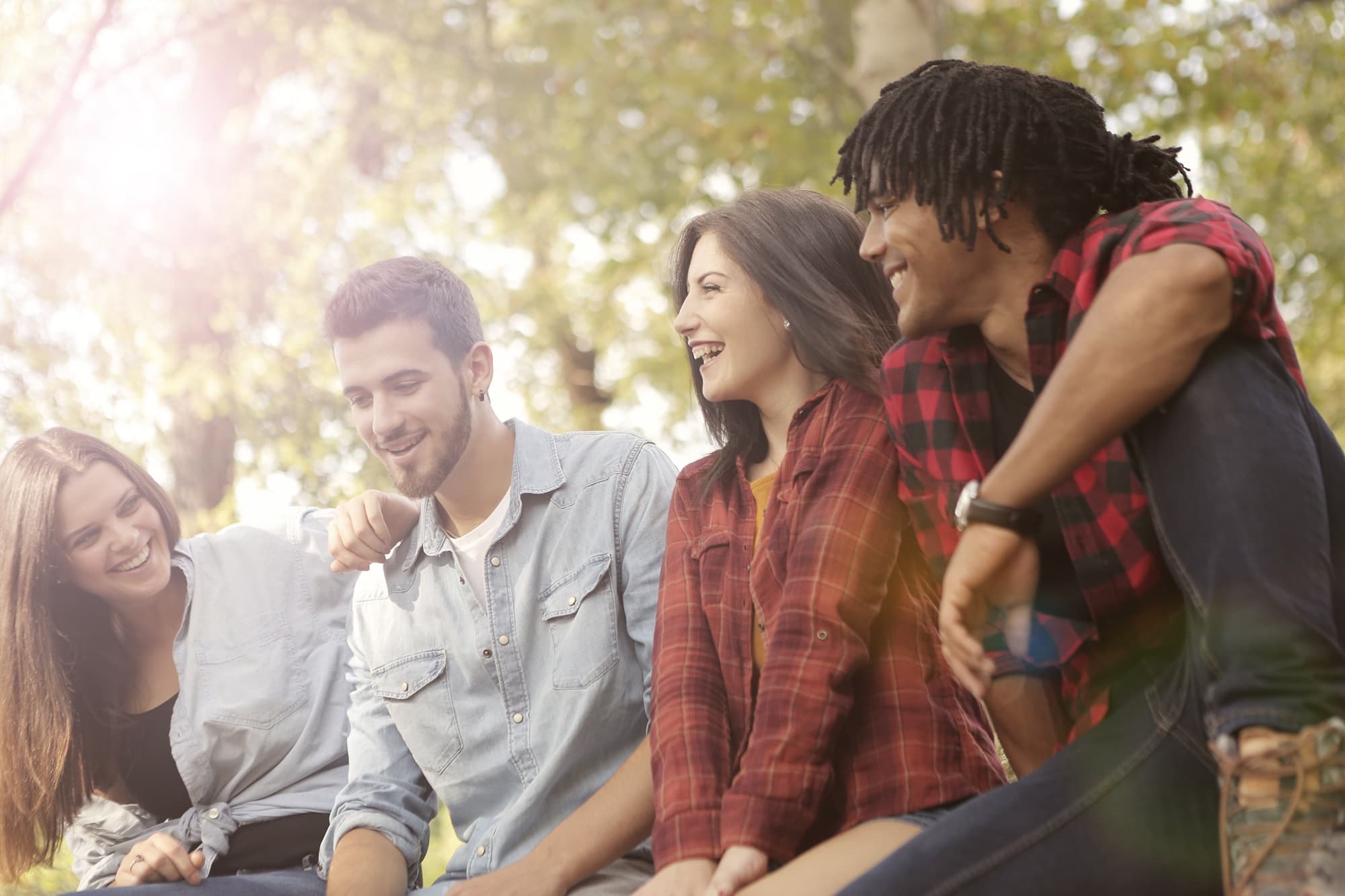 Four friends seated outdoors talking and laughing.